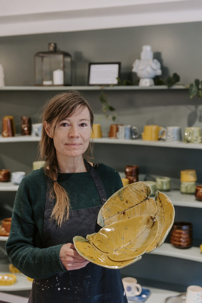 Keramisk designer Malene Sandal viser keramik frem i hendes butik.