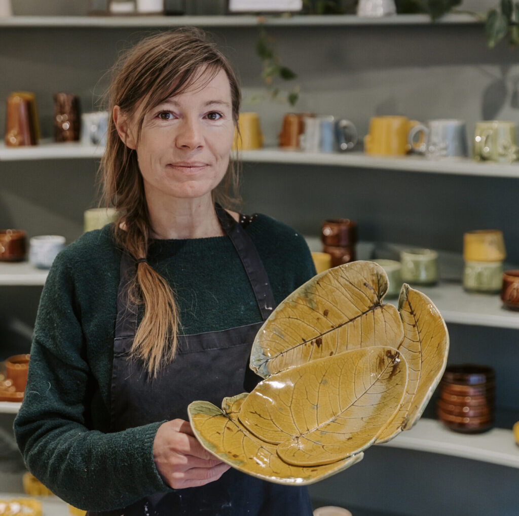 Keramisk designer Malene Sandal viser keramik frem i hendes butik.